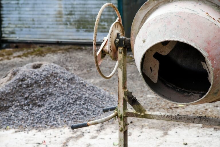 Drum concrete mixer next to a pile of gravel on a building site