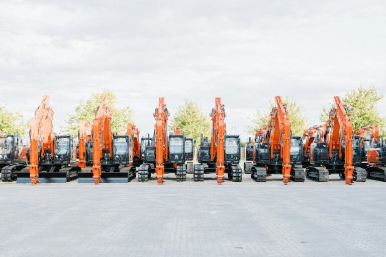 A long line of identical orange excavators parked side by side in a plant yard