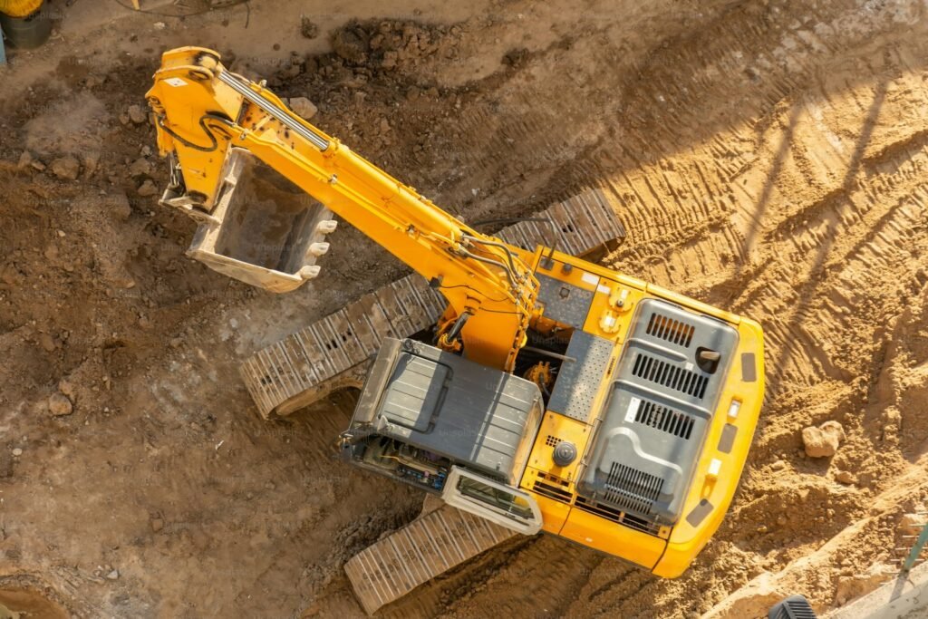 Aerial view of a yellow excavator with raised bucket on a dig site