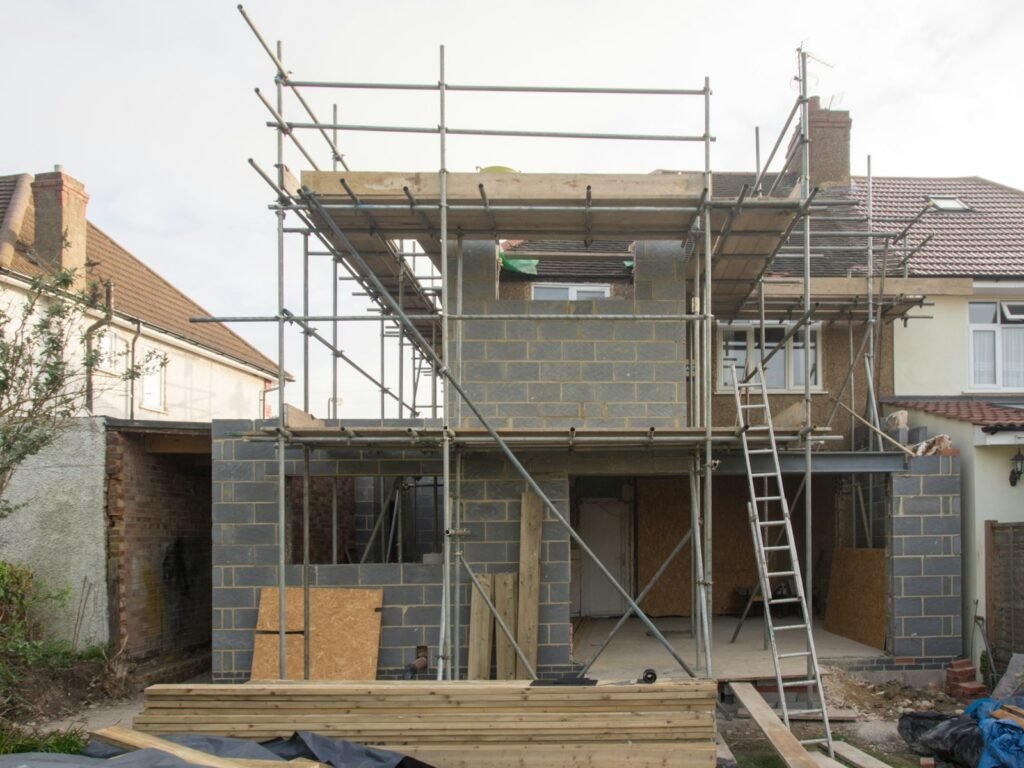 Two-storey blockwork house extension under scaffolding at the back of a British semi
