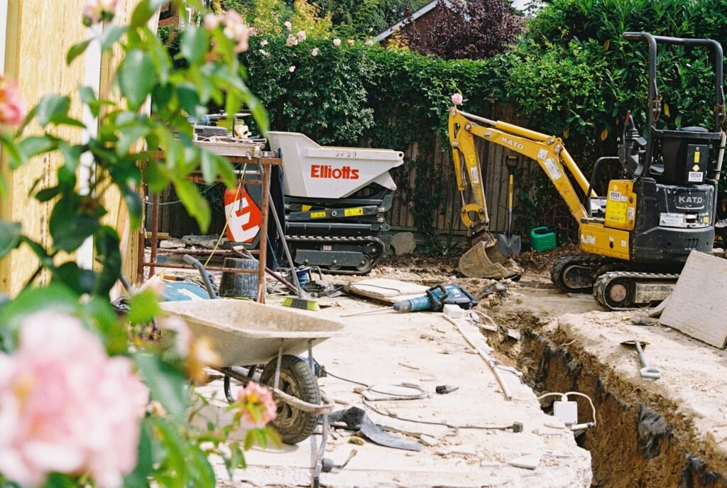 Mini digger and tracked dumper working on a garden extension site behind a UK house