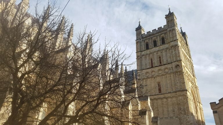 The Norman tower of Exeter Cathedral rising beside bare winter trees