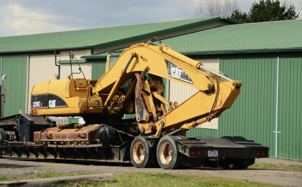 Yellow tracked excavator loaded on a low-loader trailer ready for site delivery
