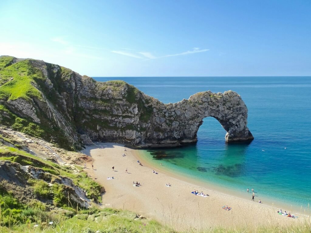 Durdle Door limestone arch and beach on Dorset's Jurassic Coast under a blue sky