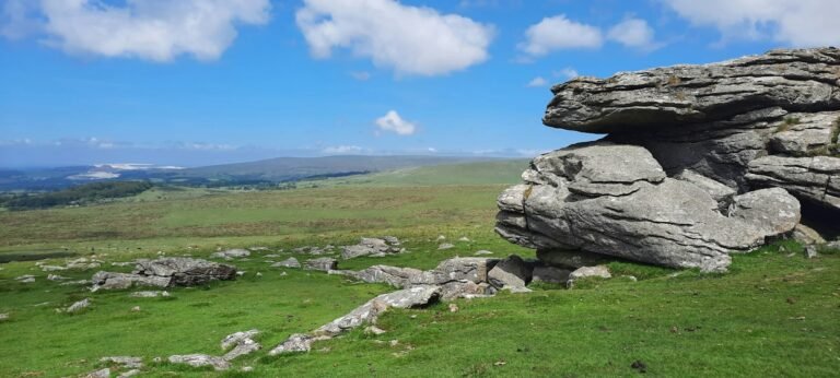 Granite tor and open moorland on Dartmoor near Okehampton under a blue sky