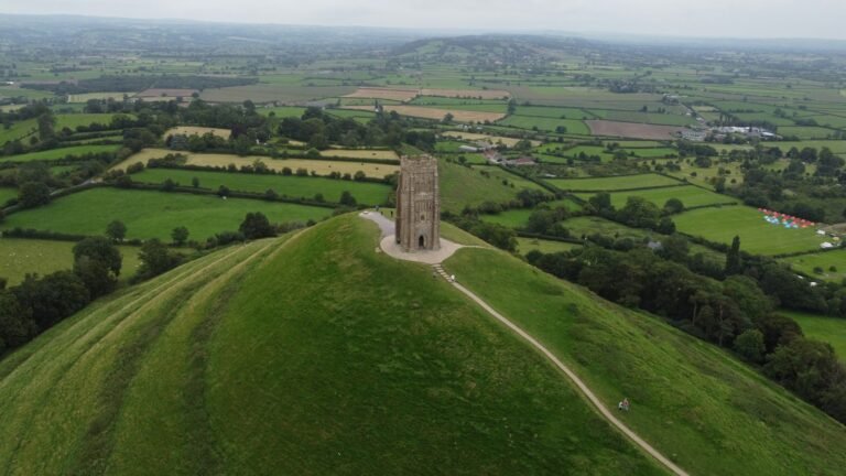 Aerial view of Glastonbury Tor and its tower above patchwork Somerset farmland