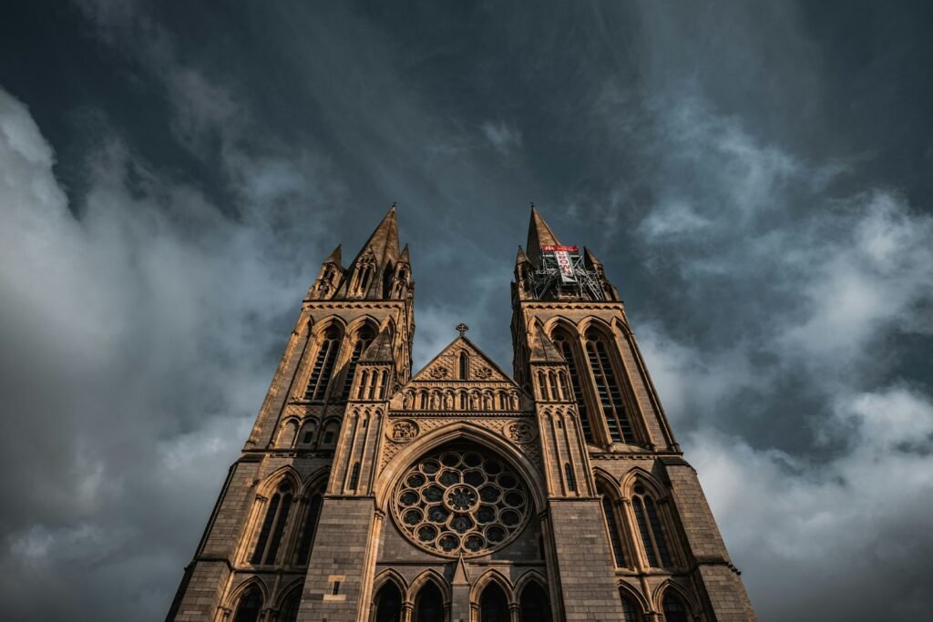 Gothic west front and twin spires of Truro Cathedral against a dramatic stormy sky