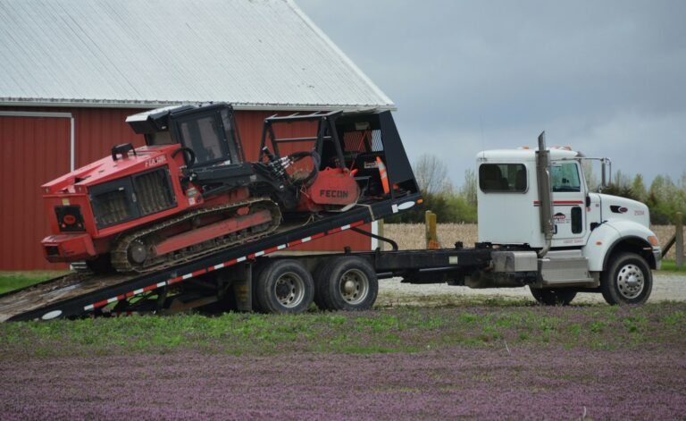 Compact tracked machine being loaded up ramps onto a plant transporter