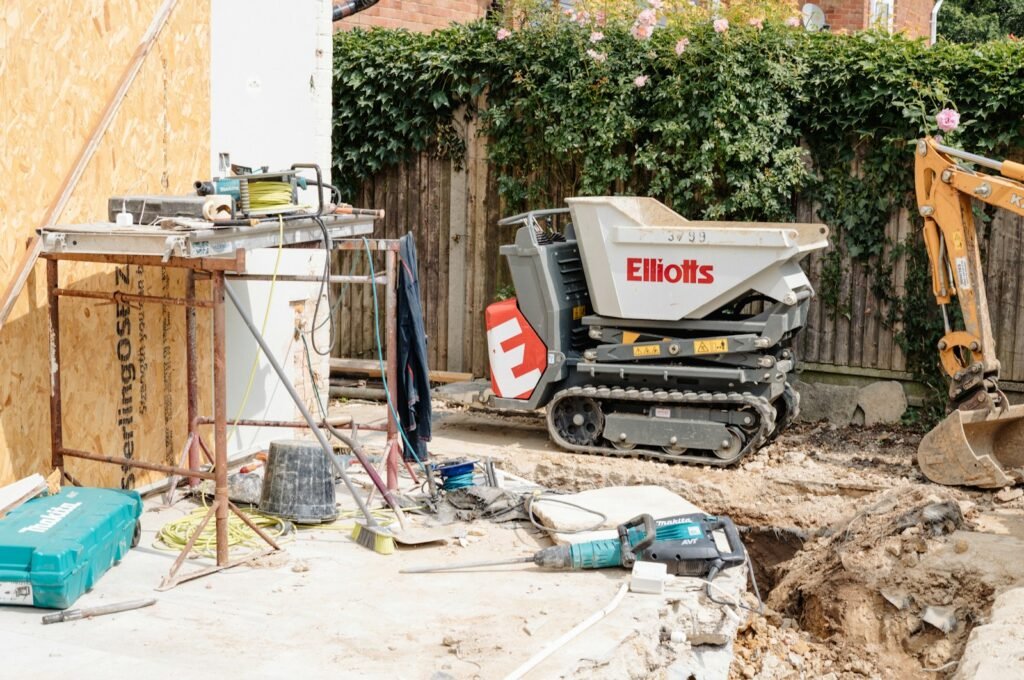 Tracked mini carrier on a narrow garden building site next to a mini digger