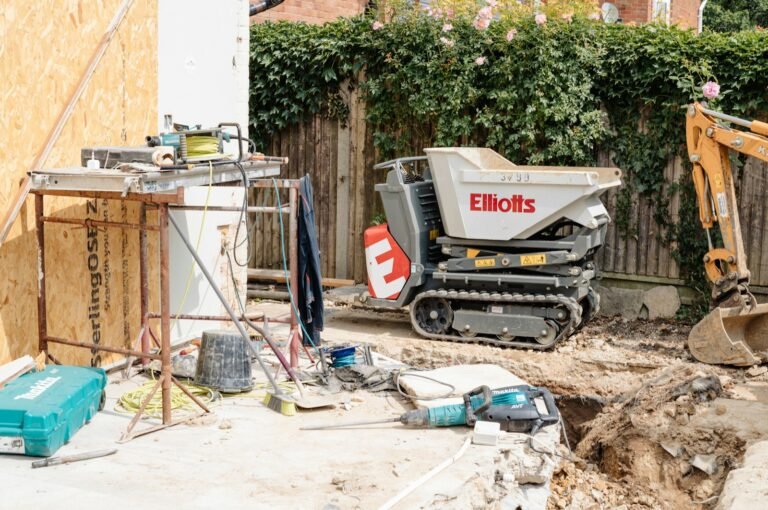 Tracked mini carrier on a narrow garden building site next to a mini digger