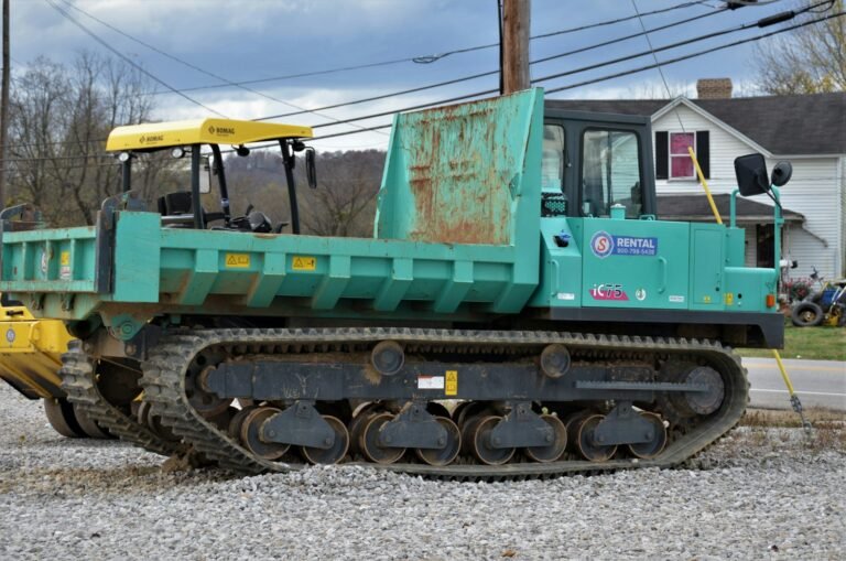 Tracked dumper with a tipping skip parked on gravel