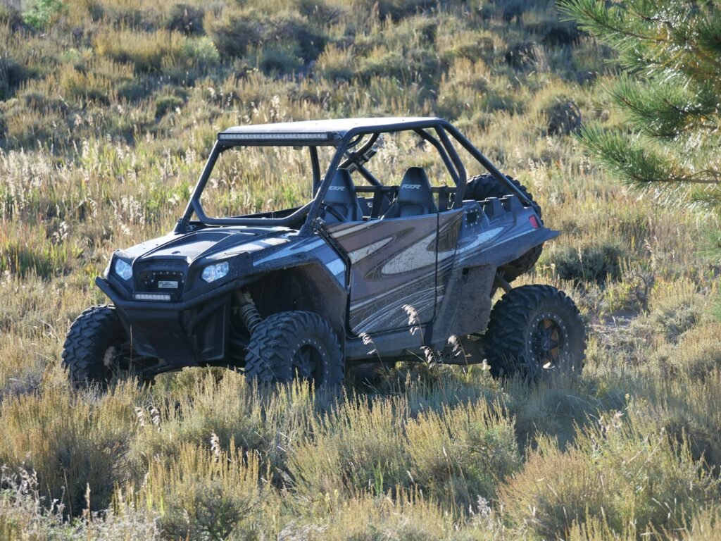 Side-by-side UTV parked in long grass in an open field