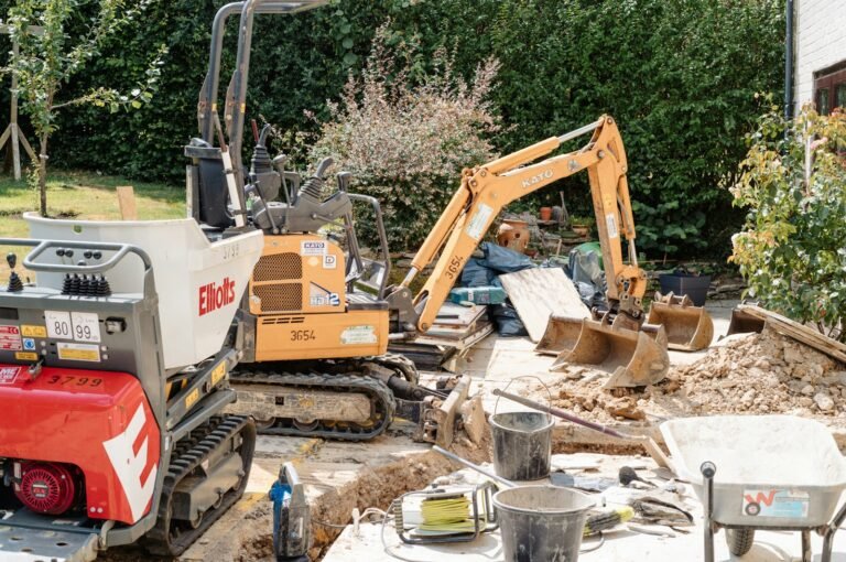 Two compact excavators and a tracked dumper working in a tight garden space